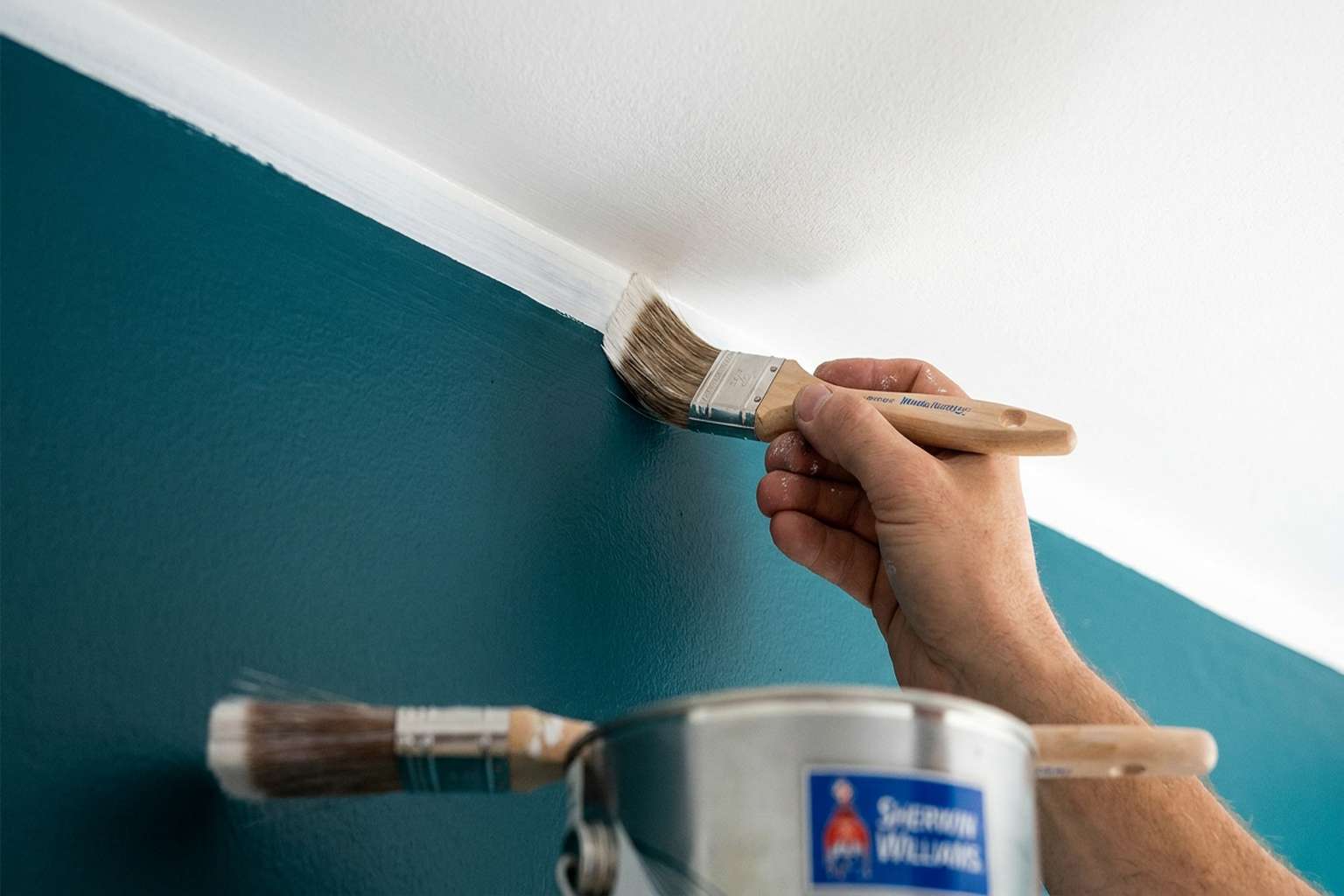 Close-up of professional painter cutting in ceiling line with brush