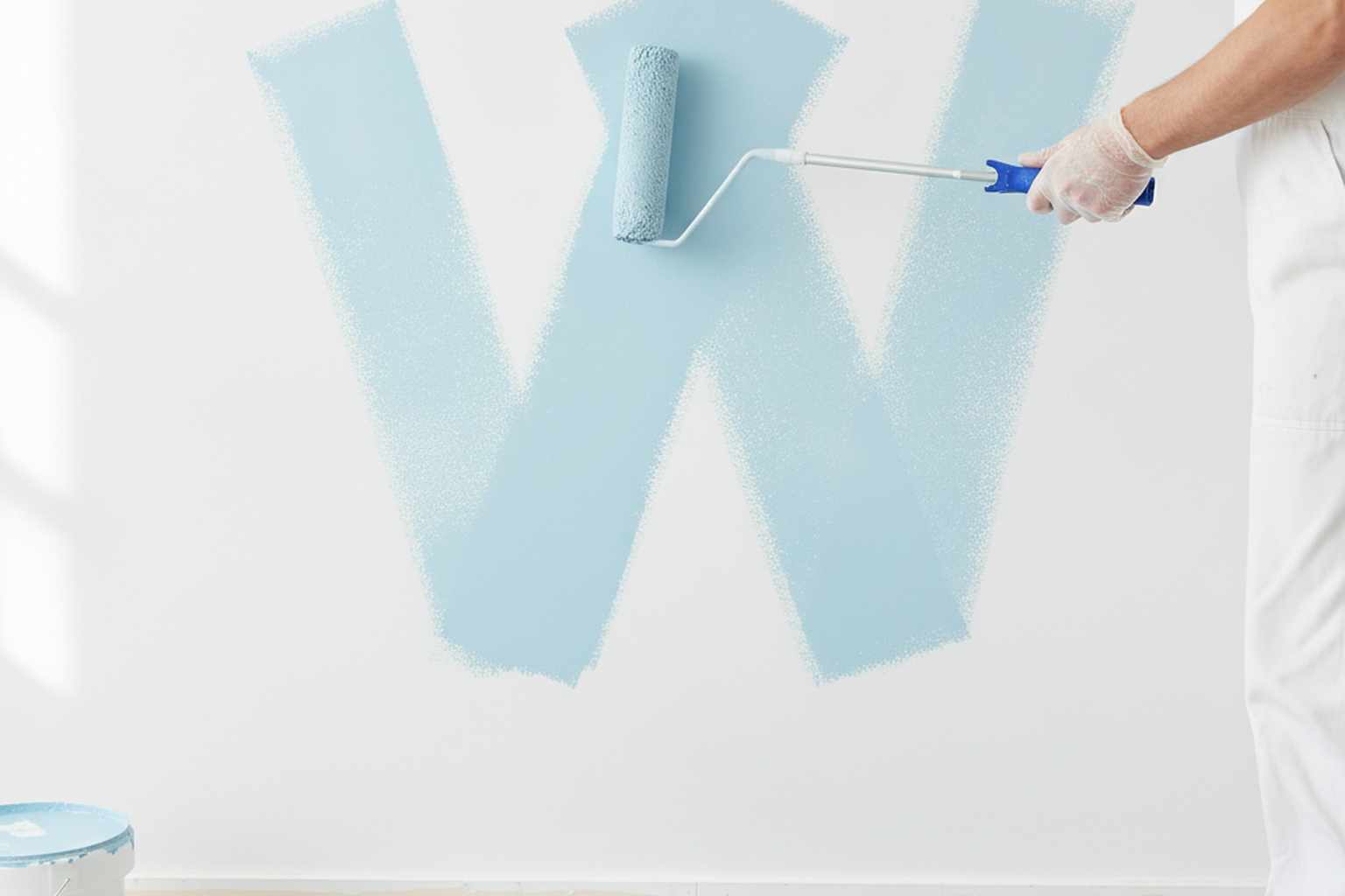 Painter rolling paint on a wall using the W technique